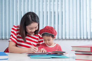 cute-boy-doing-his-school-homework-with-his-mother-home-he-is-writing-book_1249-488