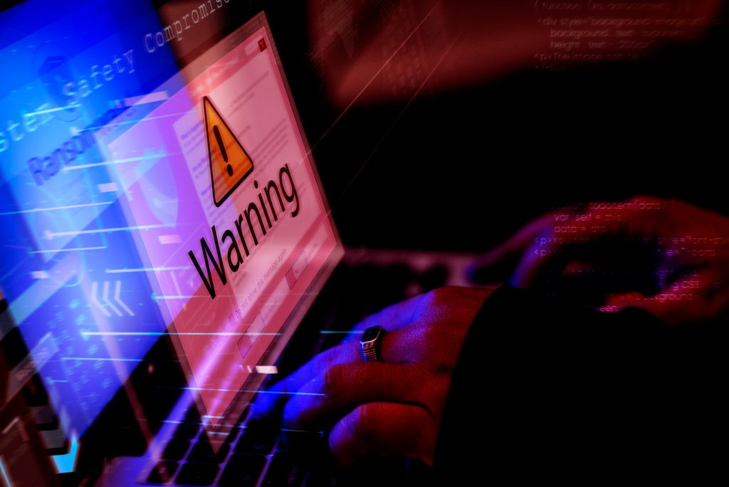 Tampilan layar laptop menunjukkan peringatan keamanan warning dalam nuansa lampu merah dan biru