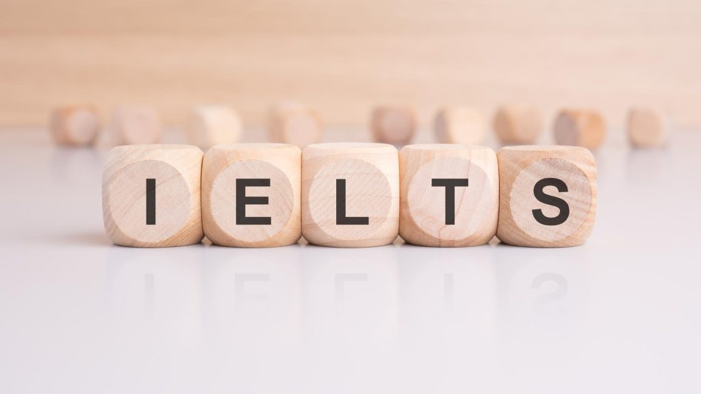 Balok kayu dengan huruf-huruf yang merangkai kata IELTS tersusun rapi di atas meja
