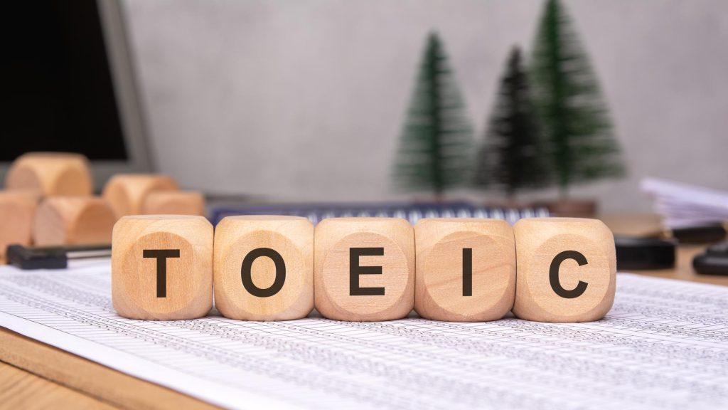 Susunan balok kayu bertuliskan TOEIC di atas lembaran kertas soal di ruang kerja