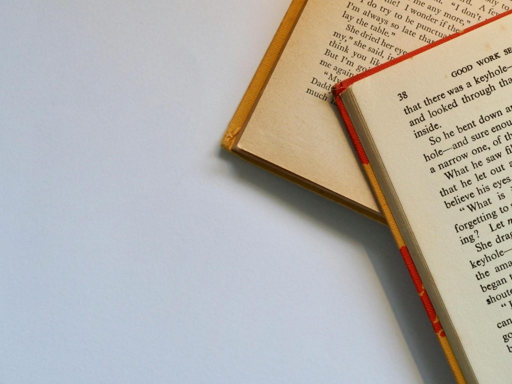 Tiga mahasiswa membaca buku bersama di perpustakaan