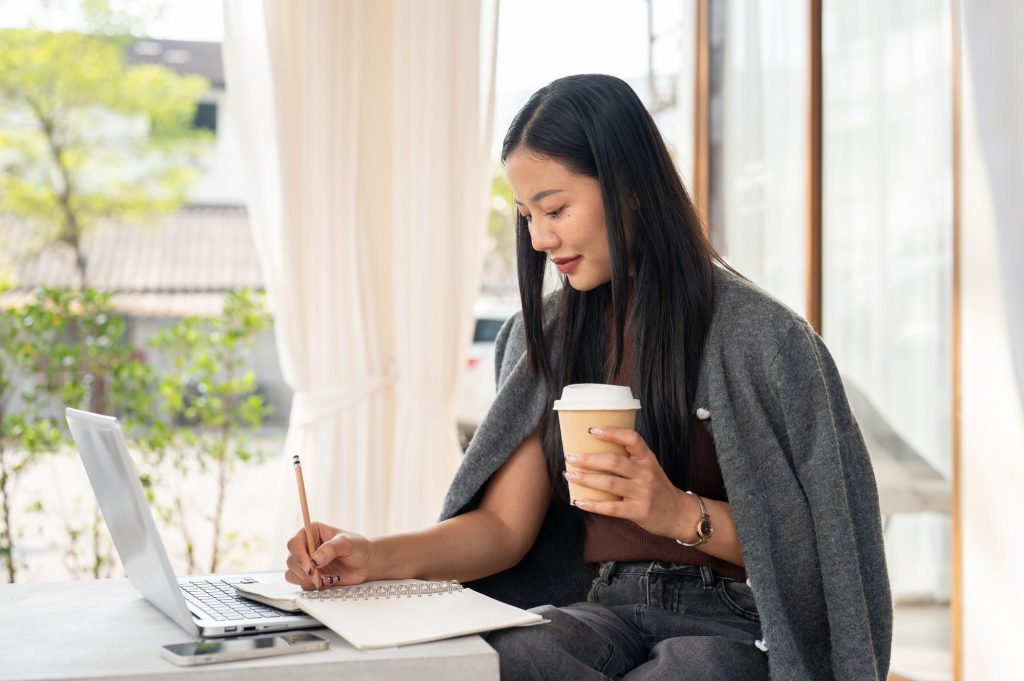 Perempuan sedang mengembangkan kemampuan menulis sambil menggunakan laptop